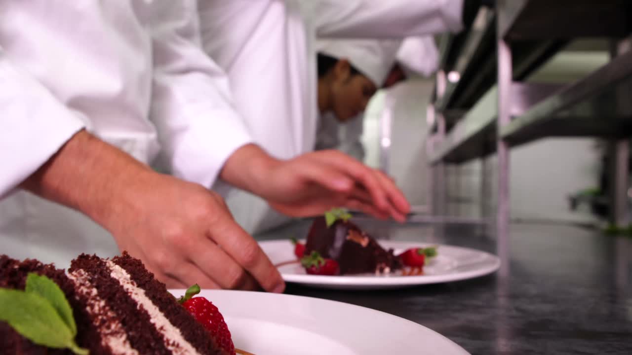 Kokketeam pynter desserttallerkener med mynteblade og jordbær