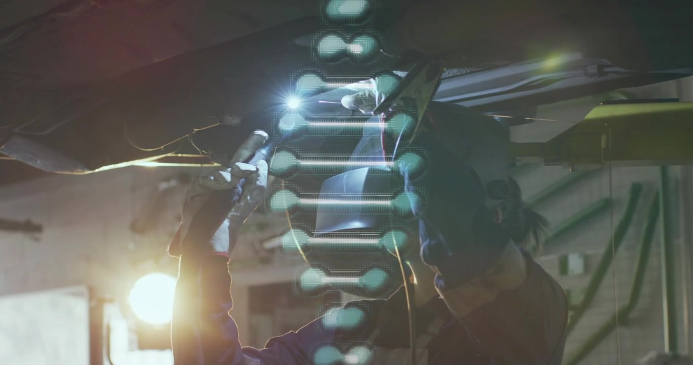 Mechanic welding beneath vehicle, raising torch to joint repairing with helix crossing frame