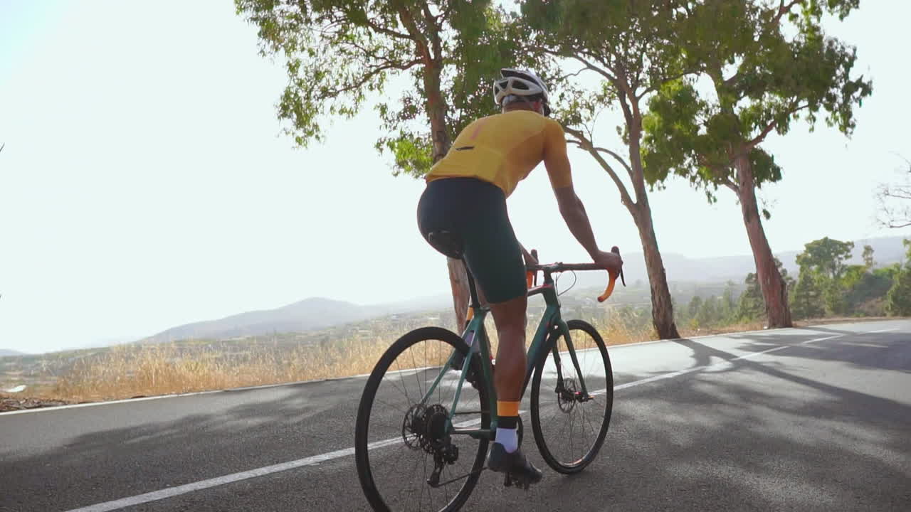 Embracing outdoor exercise, a man cycles on a road bike along an empty morning road. The slow-motion video accentuates the essence of extreme sports