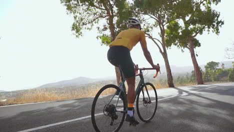 Embracing-outdoor-exercise,-a-man-cycles-on-a-road-bike-along-an-empty-morning-road.-The-slow-motion-video-accentuates-the-essence-of-extreme-sports