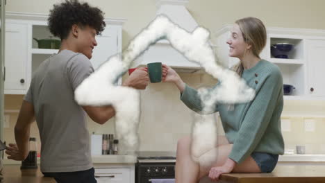 animation of cloud house over happy diverse couple toasting with tea cups in kitchen