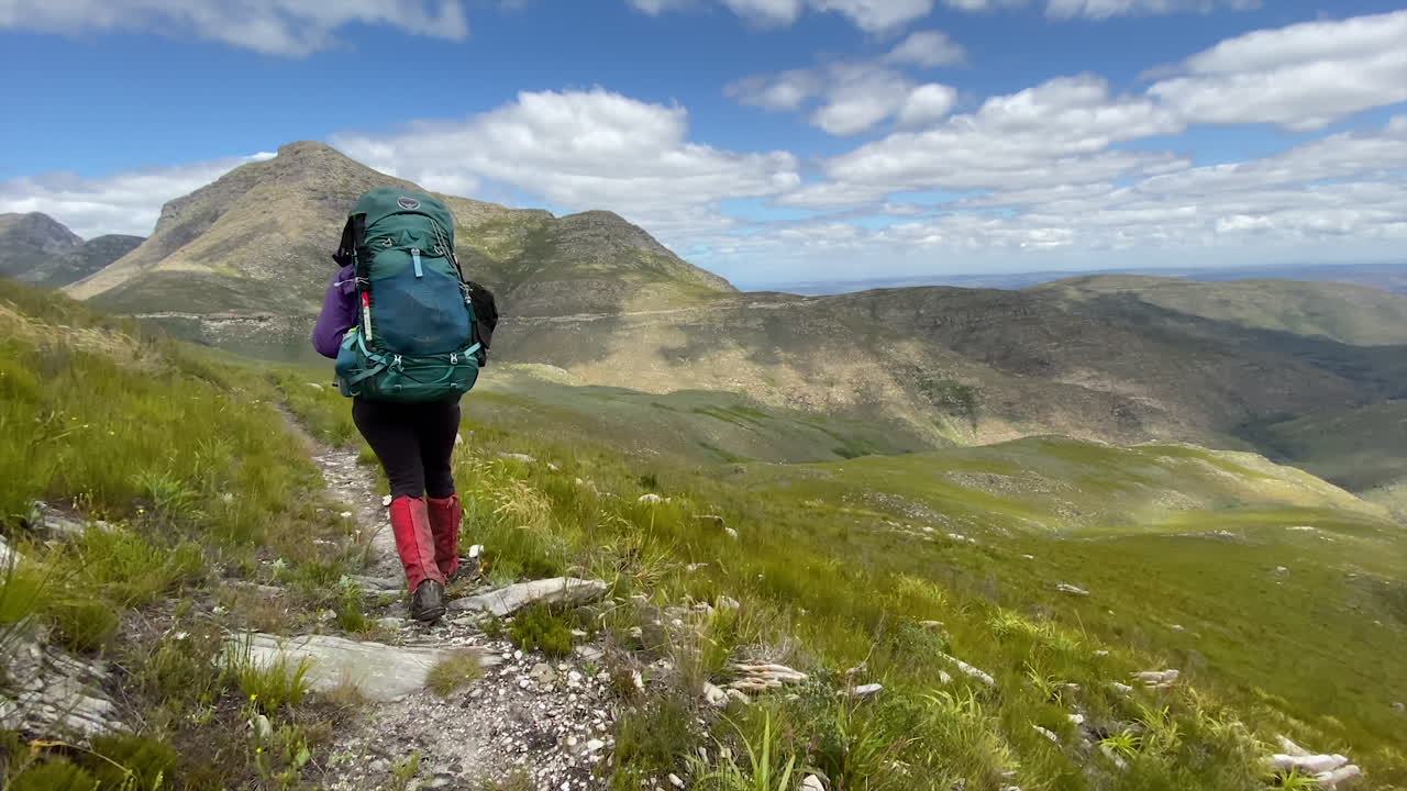 Woman traveling solo on mountain ridge path concept, breathtaking scenery