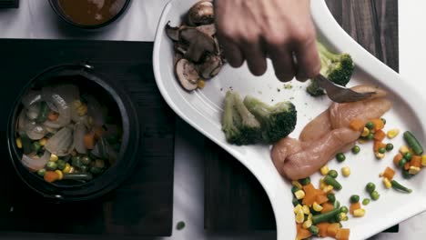 woman using a fork to put chicken in a pot