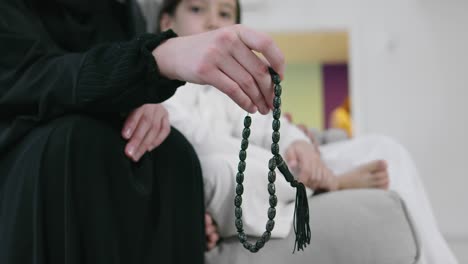 muslim woman praying at home with kid in background