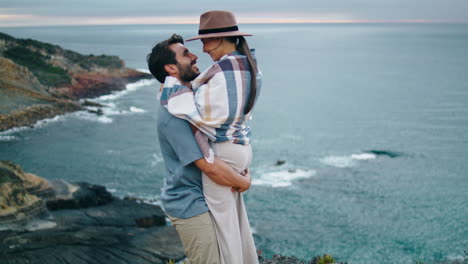 loving couple hugging coast hill. happy man spinning woman near calm ocean view