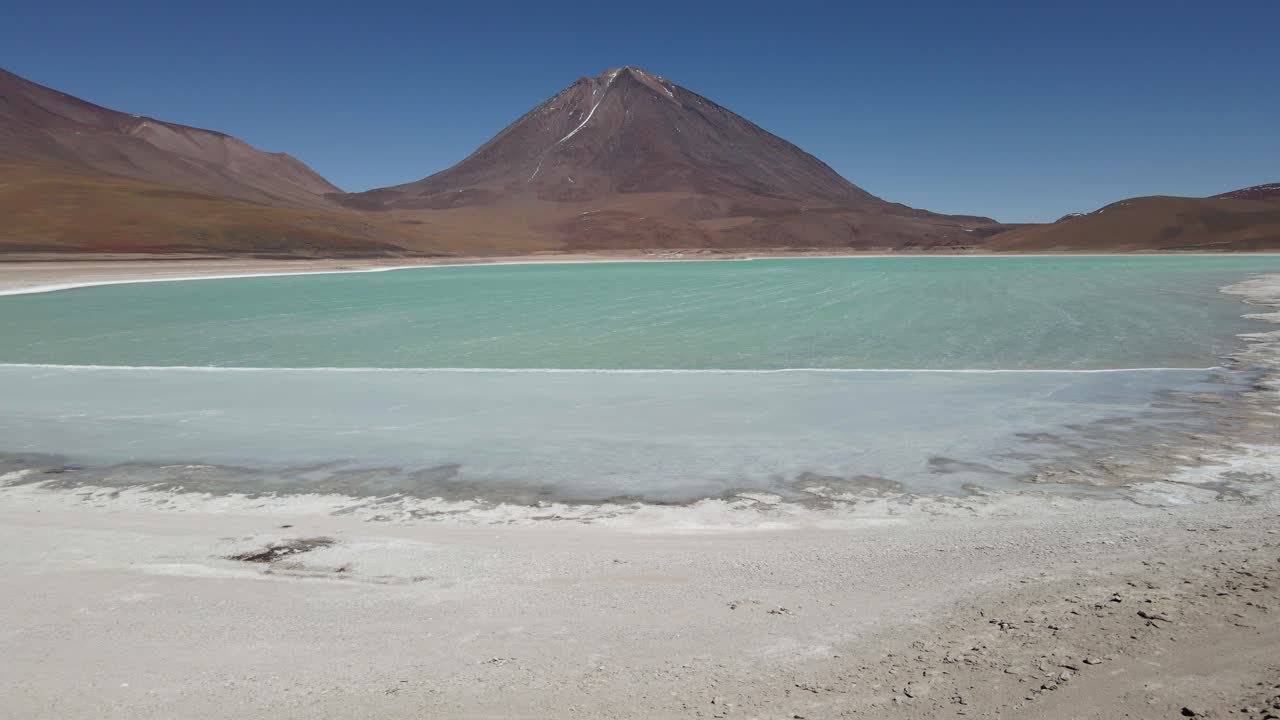 Drone reveals twin colored lakes in Bolivia surrounded by dry desert with high-altitude peaks, flyover friends taking in scenic views