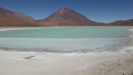 drone reveals twin colored lakes in bolivia surrounded by dry desert with high-altitude peaks, flyover friends taking in scenic views