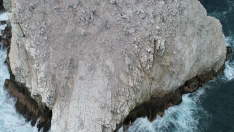 Toma-Aérea-Inclinada-Hacia-Arriba-De-Una-Gran-Formación-Rocosa-En-Playa-Zipolite,-Oaxaca