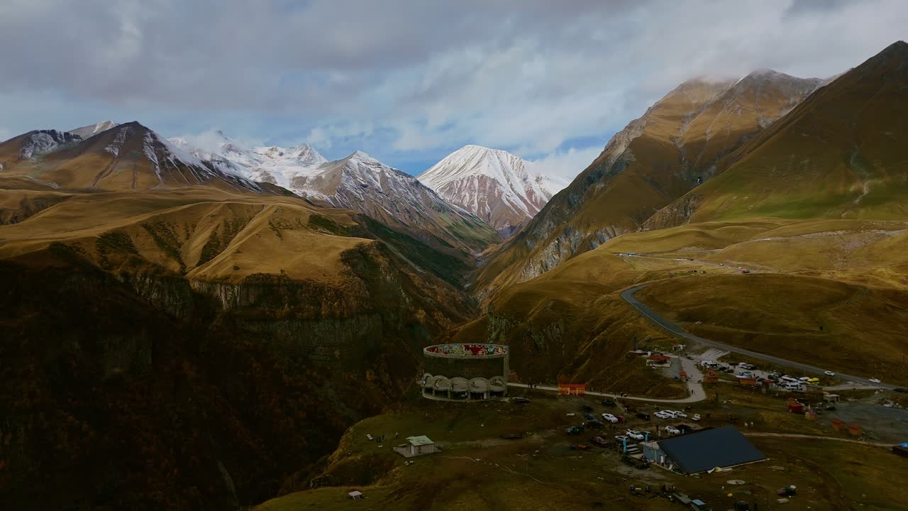 Beautiful mountain landscape of Georgia with the iconic Friendship Monument and dramatic clouds over the Caucasus range