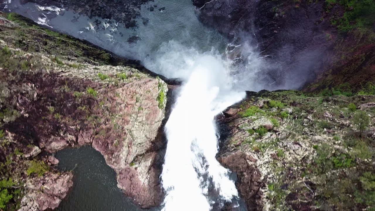 거대한 폭포 가장자리 위로 날아가면서 아래를 내려다보는 드론