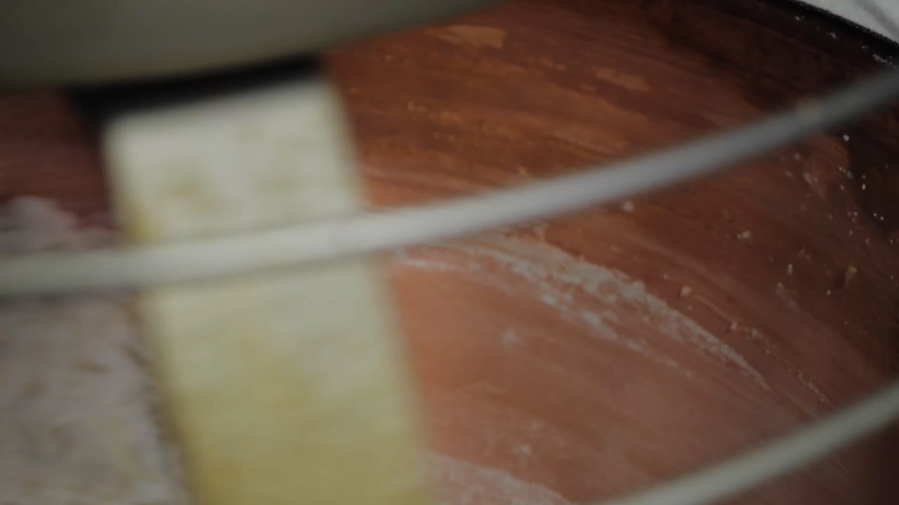 Close-up inside copper mixer slowly stirring thickening, firmer chocolate mixture in chocolate factory