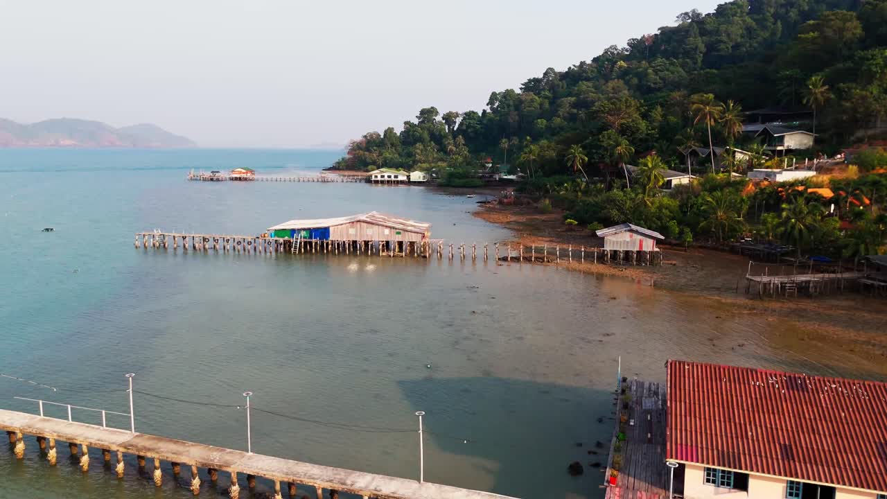Wooden bridges and houses of the beautiful Koh Chang beach, low drone flight above, along the beach, bright sunlight, tropical paradise