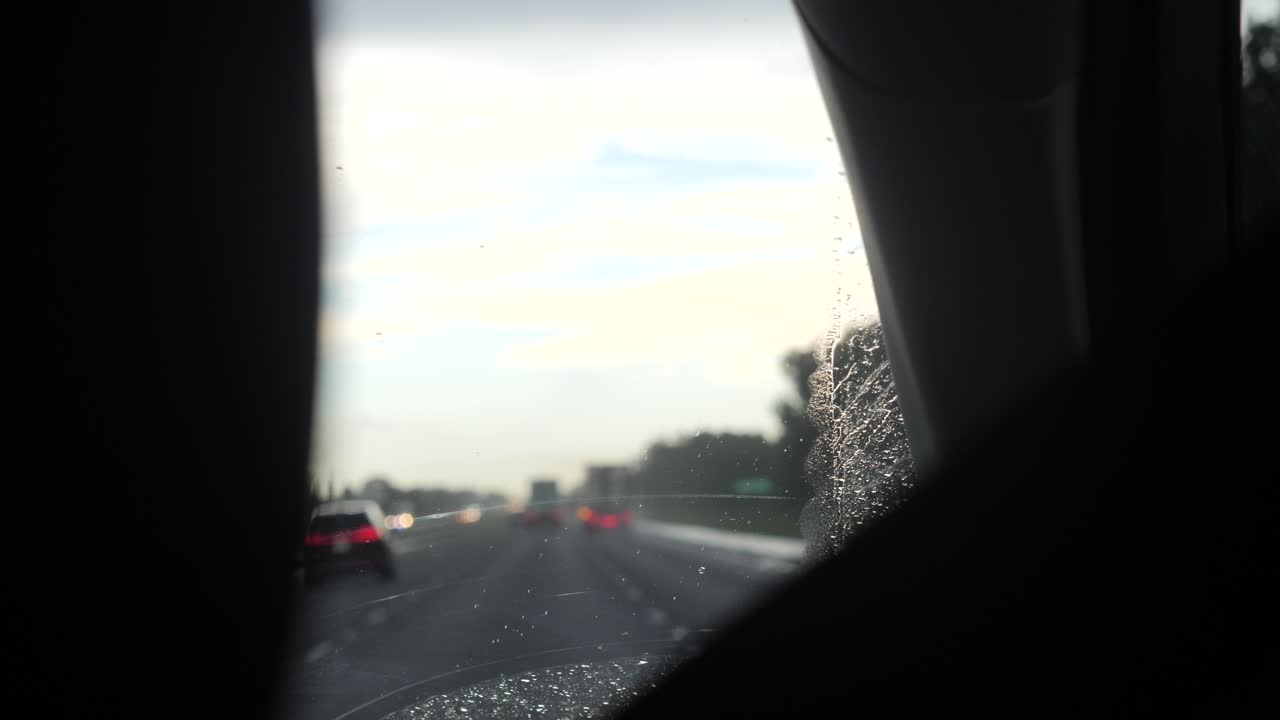 빗방울이 앞유리를 따라 슬로우 모션으로 미끄러지면서 자동차가 빗속을 달린다