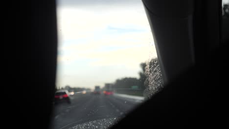 el coche conduce a través de la lluvia con gotitas deslizándose por el parabrisas en cámara lenta