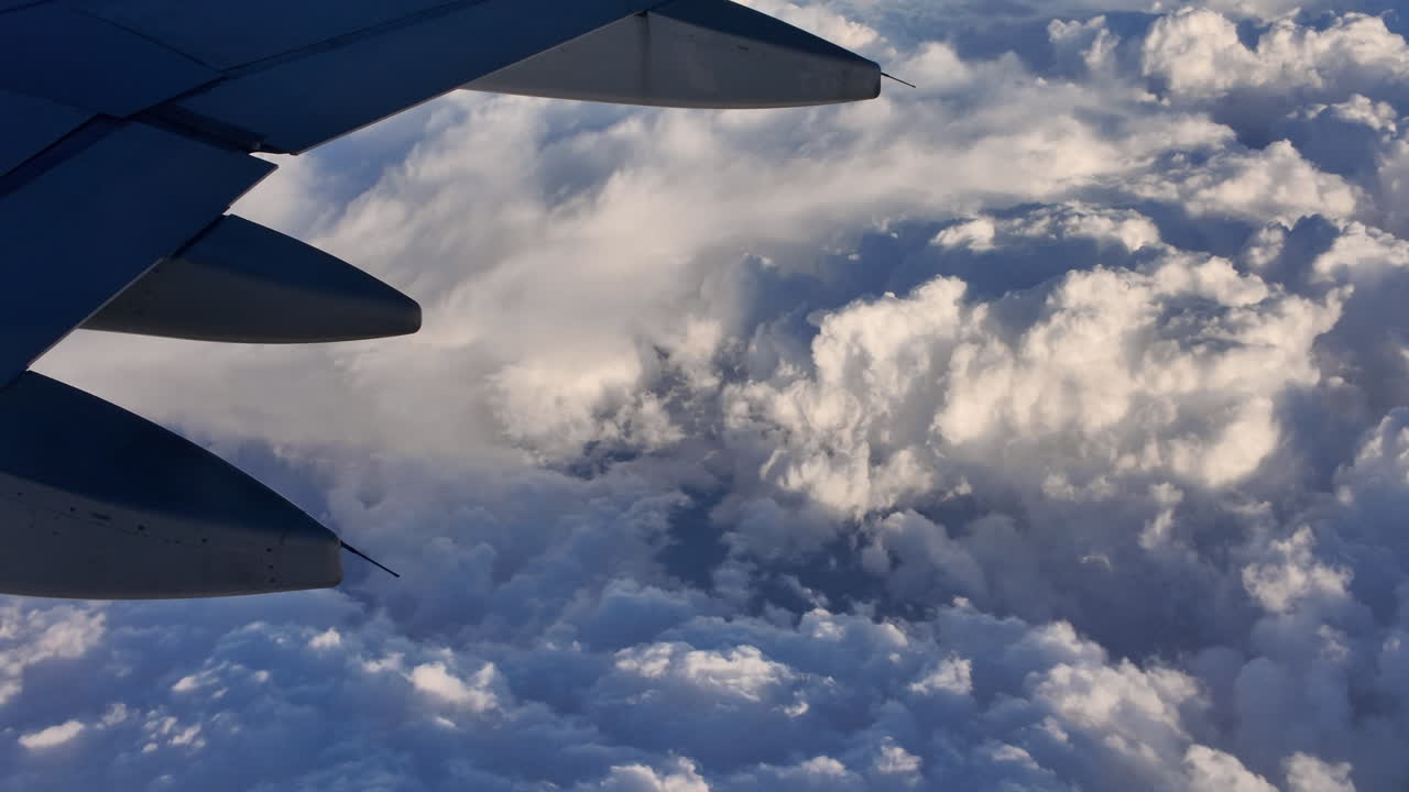 Airplane wing view over fluffy clouds during sunset flight