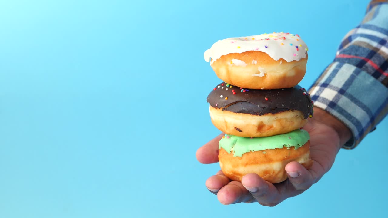una pila de rosquillas de colores en la mano