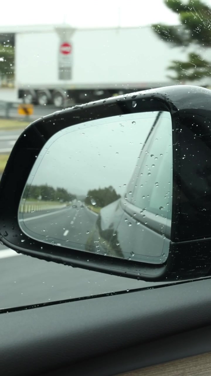 Vista dallo specchietto laterale dell'auto di un'autostrada piovosa