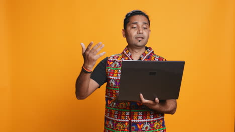 Man-with-friends-in-teleconference-meeting-using-laptop,-studio-background