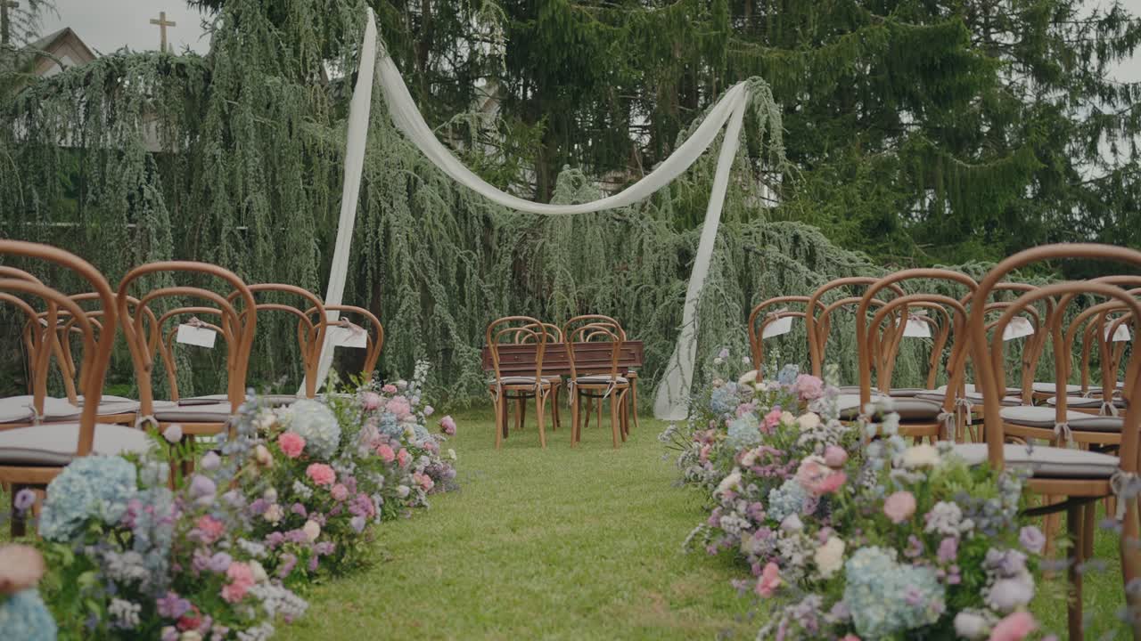 Allestimento per cerimonia nuziale in giardino con sedie in legno, fiori e arco in tessuto