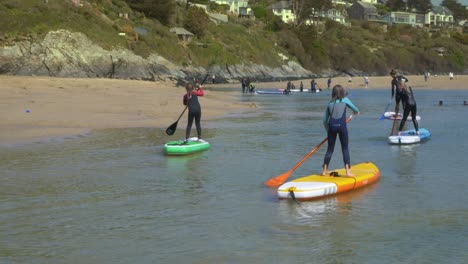 children paddleboard on a cornish beach in gentle water