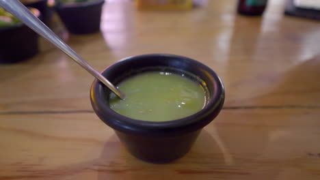 Hand-dip-tortilla-chip-into-bowl-of-green-tomato-salsa