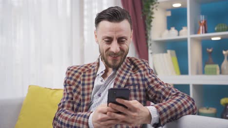 Man-looking-at-his-smartphone-is-surprised-and-smiling-wow.