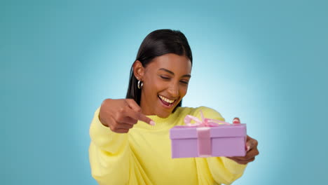 Woman,-smile-and-pointing-at-gift-in-studio