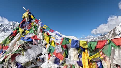 la cumbre del bajo kyanjin ri adornada con coloridas banderas de oración tibetanas, que simbolizan la paz y la compasión contra el telón de fondo del majestuoso