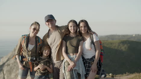 front view of a happy family standing on cliff and smiling at the camera