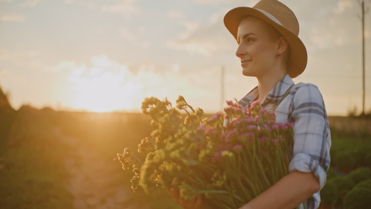 feliz jardinera que sostiene un ramo de flores al atardecer