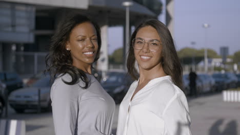 dos mujeres jóvenes atractivas posando y mirando a la cámara mientras sonríe