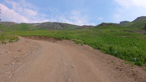 pov driving on black bear pass trail cut into hillside through alpine valley with waterfall in distance near telluride colorado