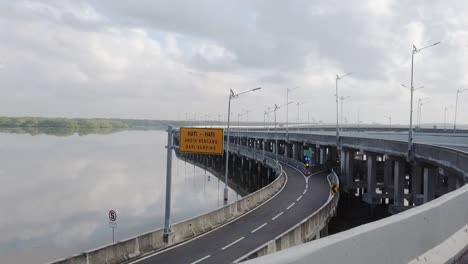 view of an empty highway toll bridges over a river with white clouds passing by at daytime