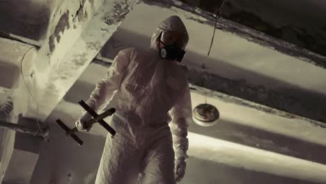 worker in protective suit inside the ruined building in abandoned area, low angle view