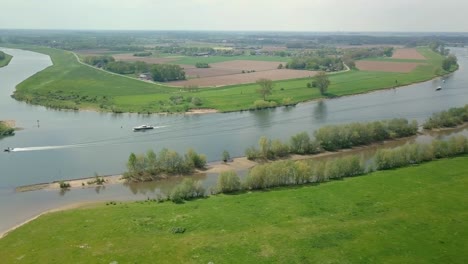 Aerial-drone-view-of-the-beautiful-river-in-the-Netherlands-and-some-boats-are-passing-by-on-the-scene