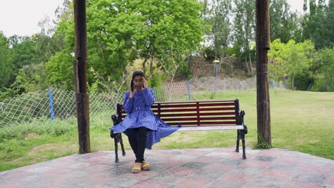 A-stressed-young-Asian-girl-sits-on-a-park-bench,-receiving-a-call,-Islamabad,-Pakistan