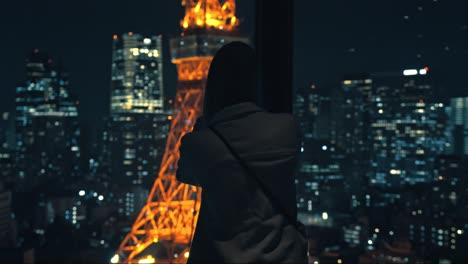 a captivating moment of a girl taking a photo of the iconic tokyo tower at night, surrounded by the vibrant city lights of tokyo.