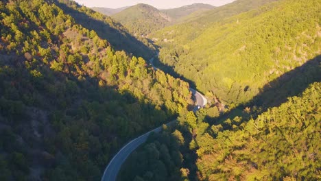 Carretera-De-Montaña-Que-Atraviesa-Las-Altas-Montañas-Y-Un-Bosque-Espeso-Tiro-De-Drones