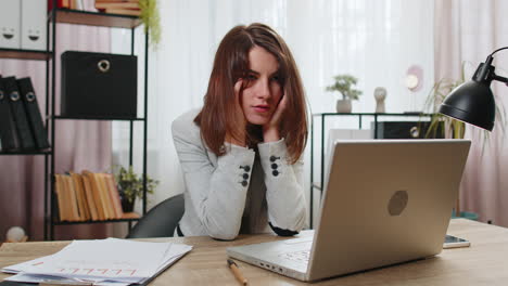 tired sleepy young businesswoman sitting at home office desk with laptop overworked lazy bored