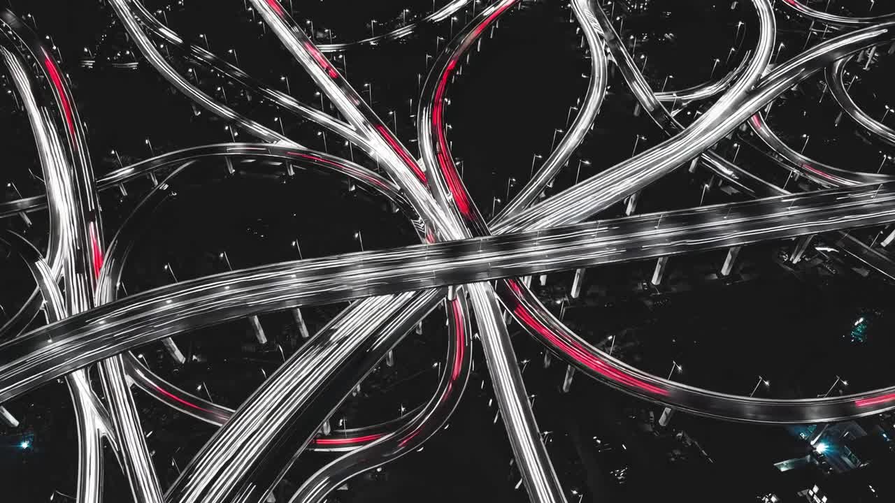 복잡한 고속도로 교차로를 드러내는 공중 풍경, 어두운 야간 도시 풍경을 통해 복잡한 빛의 흔적을 짜는 교통 인프라의 역동적인 디자인을 보여줍니다.