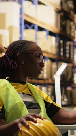 vertical video black warehouse clerks overseeing parcel status via tracking info on computer