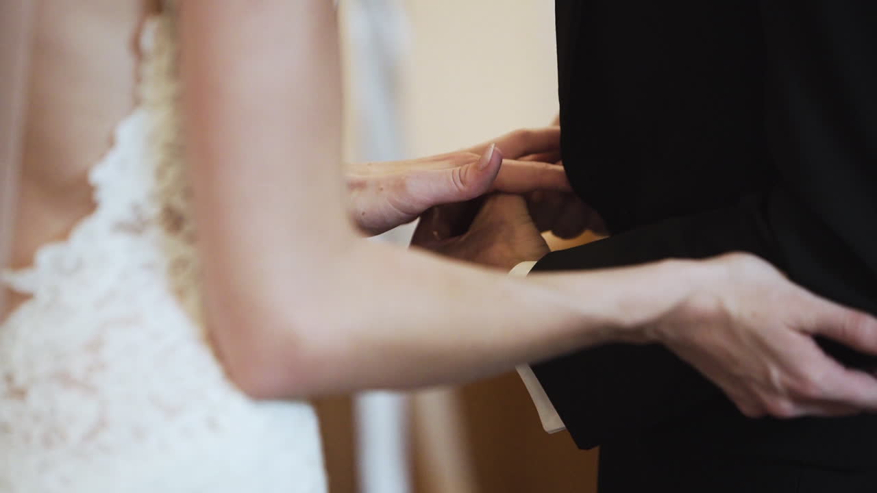 Nervous groom putting a wedding ring onto his bride's finger