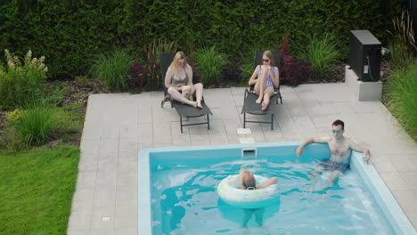 family with dog relaxing by the pool in the backyard of the house