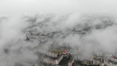 вид с воздуха на городской пейзаж сквозь медленно спускающиеся облака