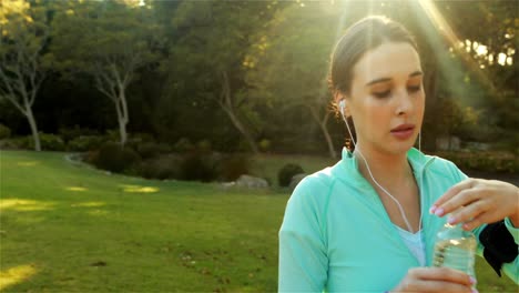 Woman-drinking-water-after-jogging-in-park