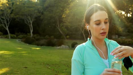 mujer bebiendo agua después de correr en el parque