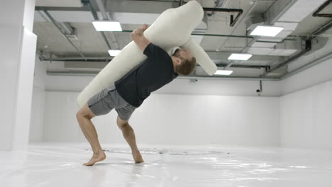 un hombre con una camiseta negra cumple lanzamientos con un espantapájaros en el tatami.