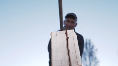 low angle shot man splits log with splitting hatchet