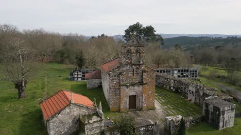 quaint mossy weathered old chapel surrounded by cemetery urn holders of church of santa maria de vilela in punxin ourense spain