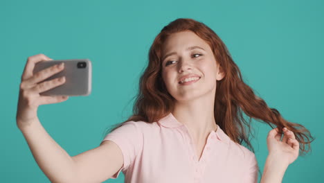 Redheaded-girl-in-front-of-camera-on-turquoise-background.